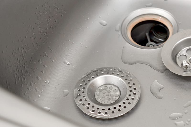 Silvery kitchen sink with disassembled protective filter during repair process